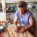 Elderly woman making cookies in kitchen