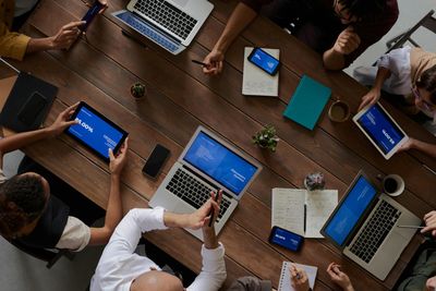 Co-workers sitting around a table with laptops and tablets