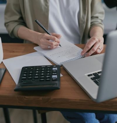 Man doing manual bookkeeping with pen, paper, and calculator