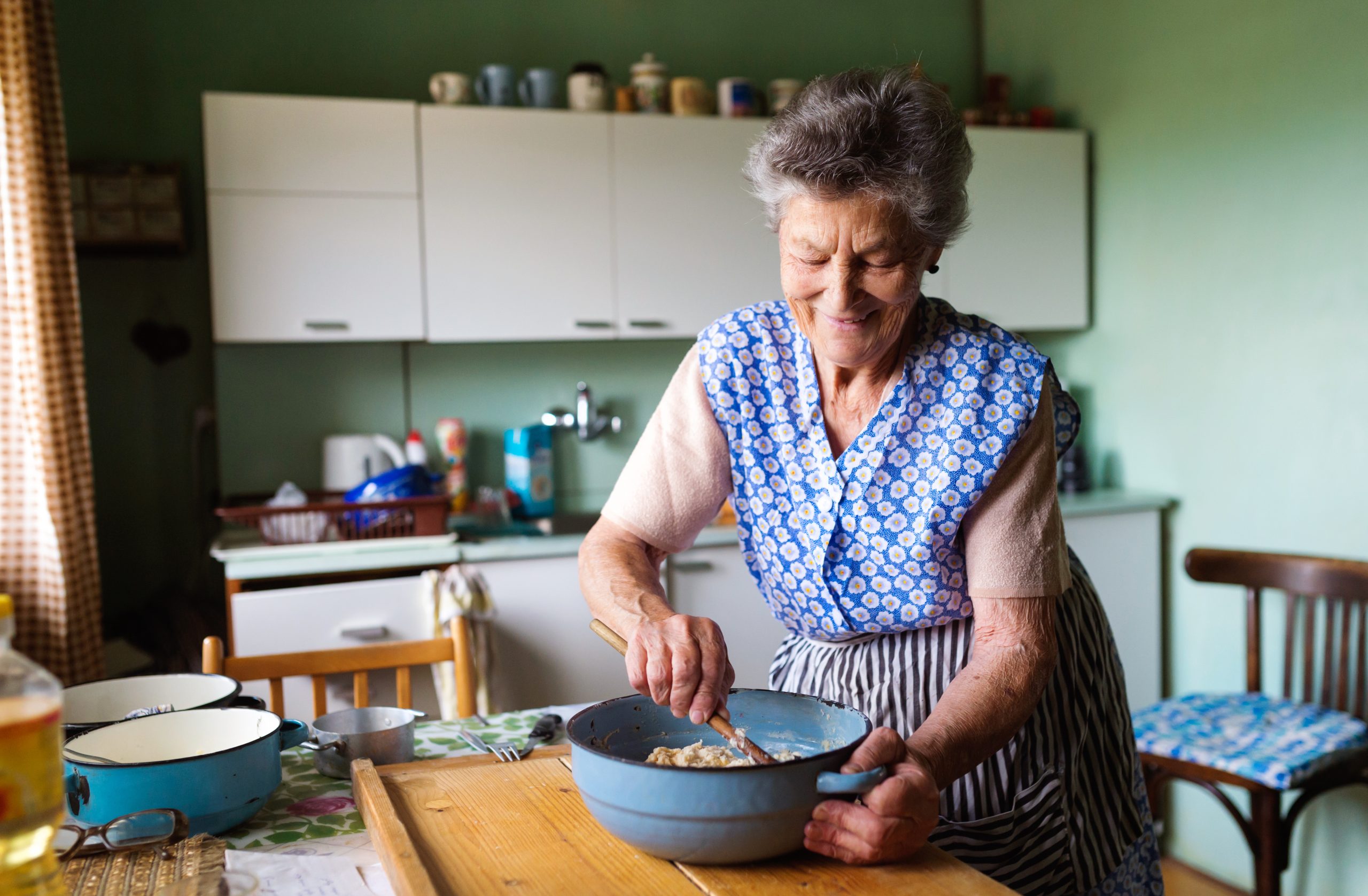 Elderly lady making cookies in kitchen