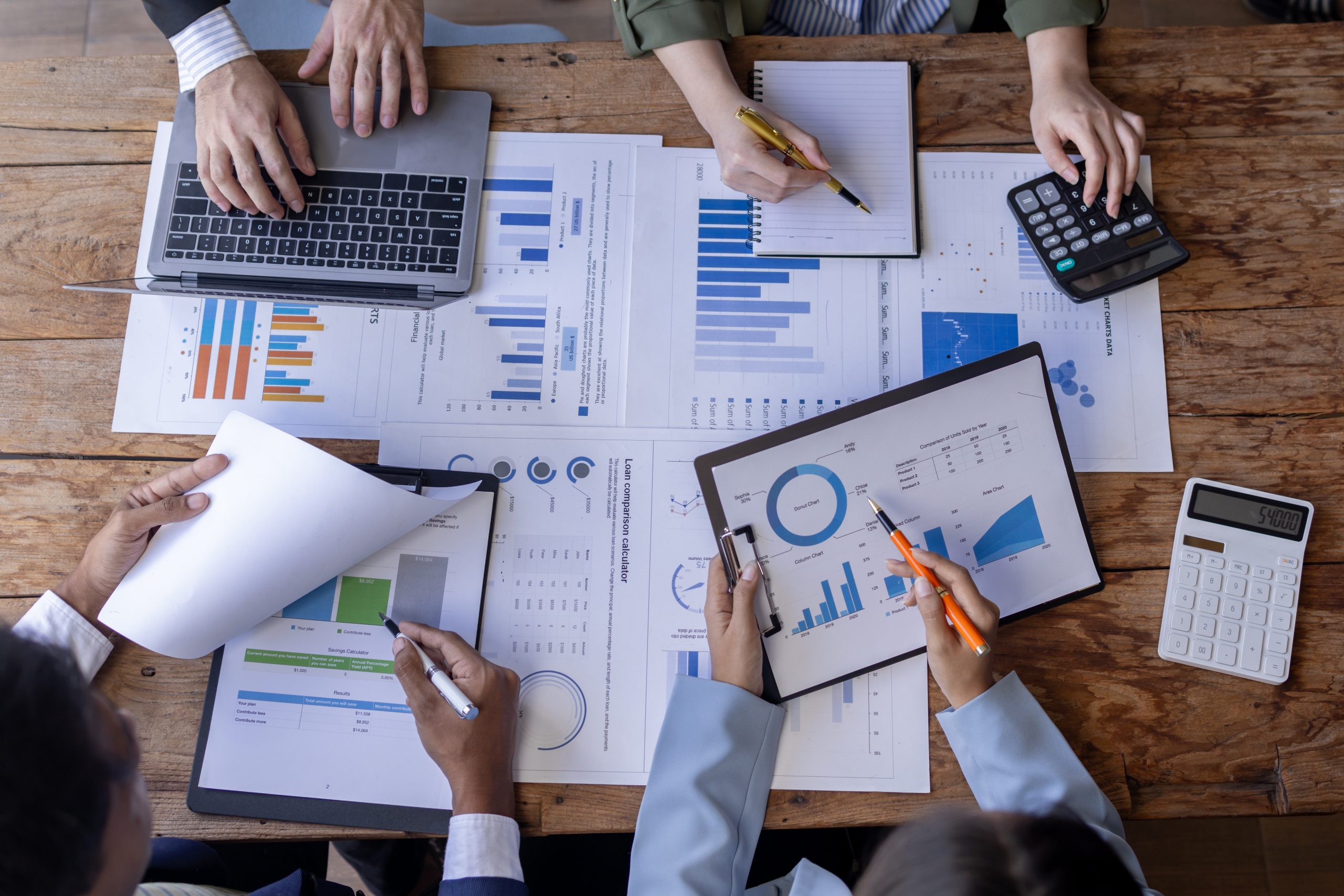 Four co-workers collaborating at a desk, interpreting financial data