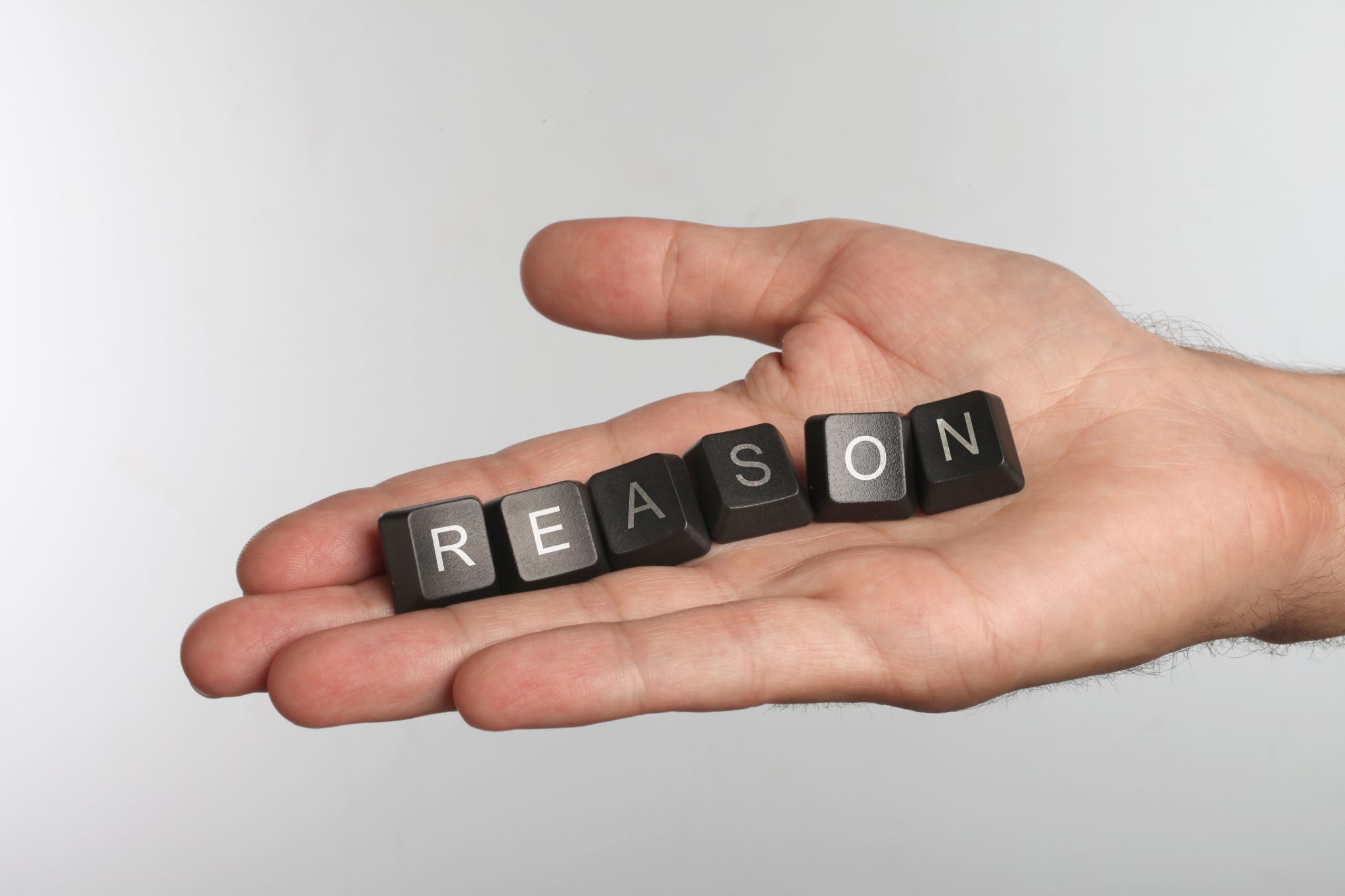 Open hand holding letter blocks that spell out R-E-A-S-O-N